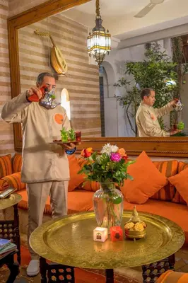 a man wearing a mask standing in a room with a table at Riad Sable Chaud in Marrakech