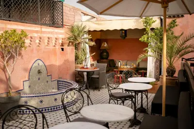an outdoor patio with tables and chairs and an umbrella at Riad Bab Chems in Marrakech