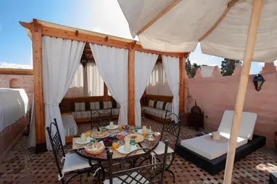 a patio with a table and chairs and an umbrella at Riad des trois palais in Marrakech