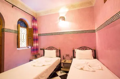 two beds in a room with pink walls at Riad Saad in Marrakech