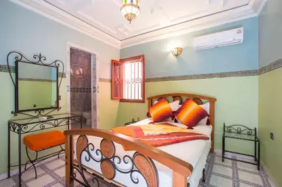 a bedroom with a bed with orange pillows and a mirror at Ryad Hamza in Marrakech