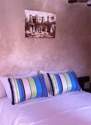 a bed with two pillows and a painting on the wall at Riad Le Bel Oranger in Marrakech