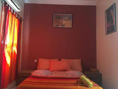 a bed in a bedroom with a red wall at Riad Hicham in Marrakech in Marrakech