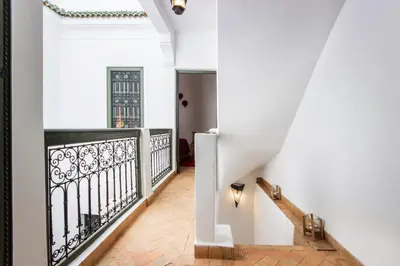 a hallway with white walls and a staircase with black railing at Riad Myla - 2mn de Jemaa El Fna in Marrakech