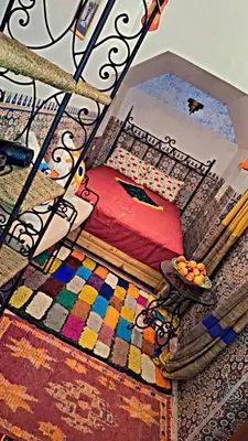 a room with a bed and a table on a rug at RIAD Redous in Marrakech