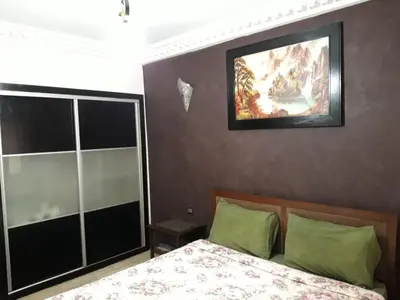 a bedroom with a bed and a painting on the wall at pascal Apartment in Marrakech