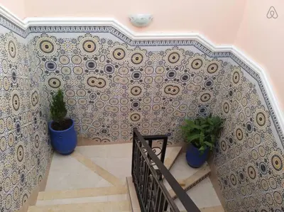 a staircase with two potted plants and a tile wall at Marrakech Family appartements in Marrakech