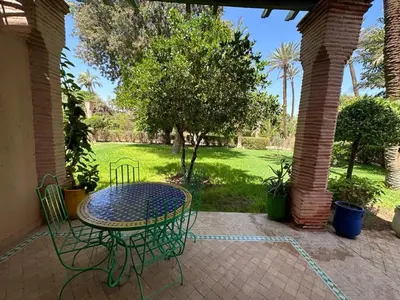 a patio with a table and chairs and a park at Palmeraie Village Appartement in Marrakech