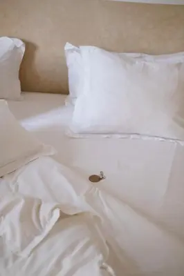 a white bed with white pillows and a small snail on it at Riad L'Atelier in Marrakech