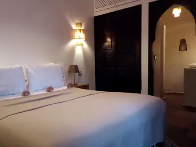 a bedroom with a white bed with a black door at Riad Bab aylen - Piscine Roof Top chauffée in Marrakech