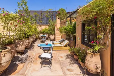 a patio with a table and chairs and potted plants at Riad Il Parco dei Principi in Marrakech