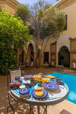a table with food on it next to a pool at Riad Il Parco dei Principi in Marrakech