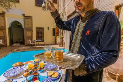 a man holding a tray of food and drinks at Riad Il Parco dei Principi in Marrakech