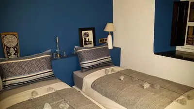 two beds in a bedroom with blue walls at Riad Bilkis Votre Maison Marrakech in Marrakech