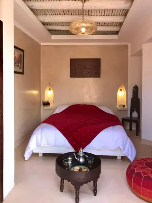 a bedroom with a bed with a red blanket and a table at Riad Zahir in Marrakech