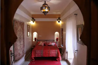a bedroom with a red bed and a chandelier at Riad Couleurs du Sud in Marrakech