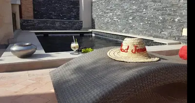 a straw hat sitting on a table next to a pool at Riad Jenaï L'Authentique in Marrakech