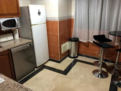 a small kitchen with a refrigerator and a stool at Annakil Appart in Marrakech