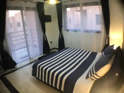 a bedroom with a bed with a blue and white striped blanket at Annakil Appart in Marrakech