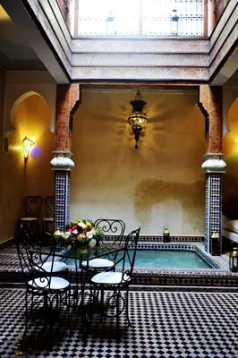 a room with a table and chairs and a pool at Riad Charik in Marrakech