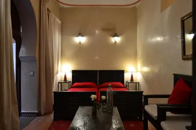 a bedroom with a bed with red pillows and a table at Riad Charik in Marrakech