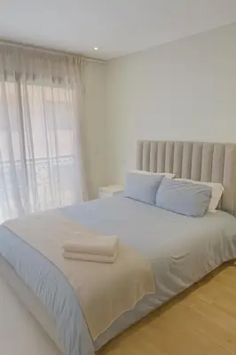 a white bedroom with a large bed with blue pillows at Apt standing 80m2, 2 chambres, terrasse, piscine in Marrakech