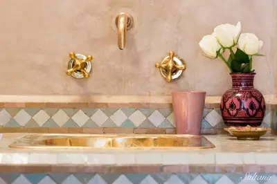 a bathroom sink with a vase and flowers on a counter at Riad El Maktoub in Marrakech
