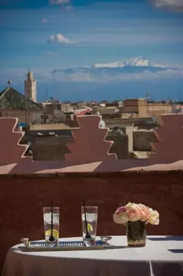 a table with two glasses and a vase with flowers at Riad Zamzam & Spa in Marrakech