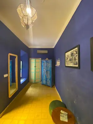 a room with blue walls and a table and a chandelier at Riad Milouda in Marrakech