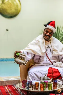 a man in a santa hat sitting in a chair with a tray of food at Riad Milouda in Marrakech