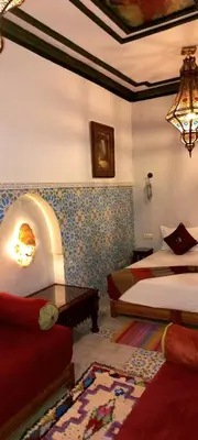 a bedroom with two beds and a table in a room at Riad Basma Marrakech in Marrakech