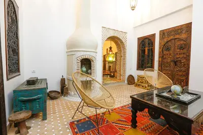 a living room with a table and chairs and a fireplace at Riad Dada Mouss & Suites in Marrakech