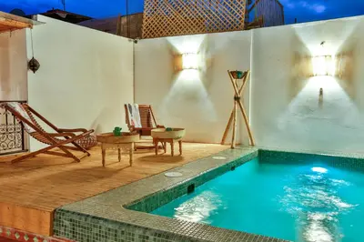 a swimming pool with a table and a chair next to it at Riad Dada Mouss & Suites in Marrakech