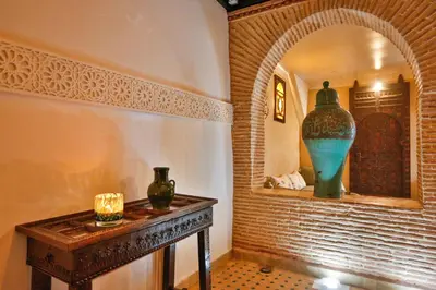 a room with a table with a large vase on a wall at Riad Dada Mouss & Suites in Marrakech