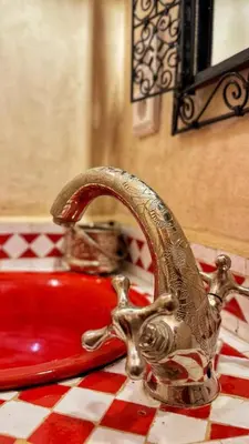 a bathroom sink with a chrome faucet next to a red sink at Riad Dada Mouss & Suites in Marrakech