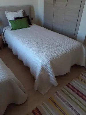 a white bed with a green pillow on top of it at Jade Golf City in Marrakech