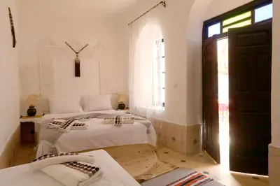 two beds in a white room with a window at Riad Capri in Marrakech