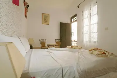 a white bed in a white room with two pillows on it at Riad Capri in Marrakech