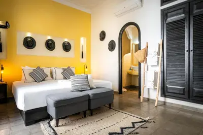 a bedroom with a white bed and a yellow wall at Riad Come & Va Medina in Marrakech