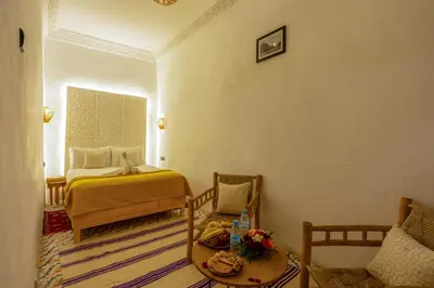 a bedroom with a bed and a table and chairs at Riad des remparts Marrakech in Marrakech