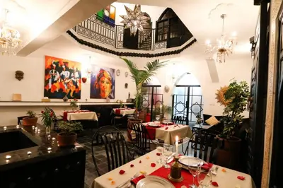 a restaurant with tables and chairs and paintings on the wall at La Voûte Étoilée in Marrakech