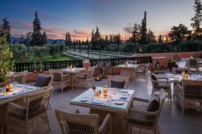 a restaurant with tables and chairs with a sunset in the background at The Oberoi Marrakech in Marrakech