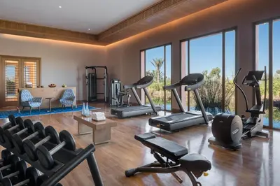 a gym with treadmills and exercise equipment and windows at The Oberoi Marrakech in Marrakech