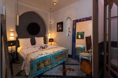 a bedroom with a large bed and a mirror at Riad Lumière in Marrakech
