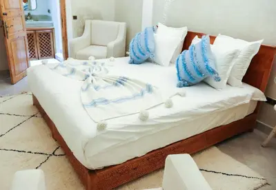 a bed with blue and white pillows on it at Riad azra Marrakech in Marrakech