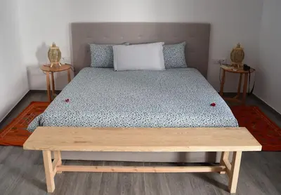 a bedroom with a bed with a wooden bench on it at Riad Dar DARRE in Marrakech