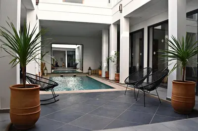 a swimming pool with two chairs and two potted plants at Riad Dar DARRE in Marrakech