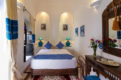 a bedroom with a bed and a table and a mirror at Riad Al Jana in Marrakech