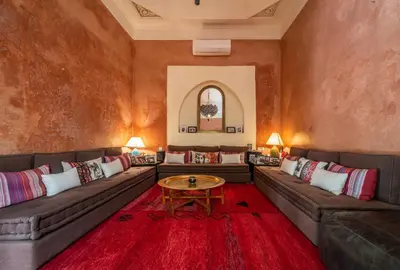 a living room with couches and a table on a red rug at Riad Adilah Marrakech - by EMERALD STAY in Marrakech