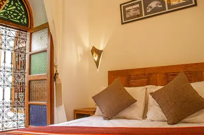 a bedroom with a bed with white sheets and a window at Riad Dar Tamlil in Marrakech